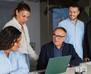 Consultants sitting around a laptop at a table.