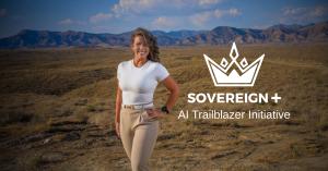 Dr. Elisa Jones standing in a desert open space with ragged hills in the background. She wears a smile, white shirt, and her hair is blowing in the wind.