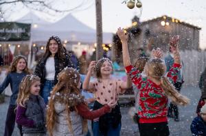 Kids playing and catching snowflakes at the Holiday Village Market