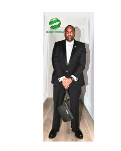 Portrait of CEO Slow wearing a black tuxedo, standing in a hallway with the Secret World logo above him, representing his new role as strategic partner for Secret World.