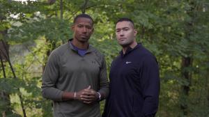 Two men standing in a wooded area, symbolizing the calm and presence that help open conversations within the Grabbterapi (Dude Therapy) concept.