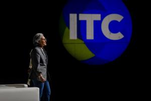 Grace Hanson, founder and CEO of Elysian, on stage delivering her winning pitch from the State Farm Startup Pitch Competition, during InsureTech InsureTech Connect (ITC) conference 2025, standing in front of a large illuminated ITC logo projected on a dar