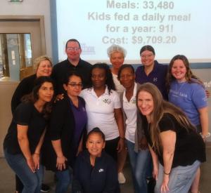 The team posing in front of the Feed My Starving Children slide showing that their work will feed 91 kids for one year.