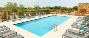 A sparkling blue swimming pool surrounded by lounge chairs and vibrant greenery, creating a serene outdoor retreat.