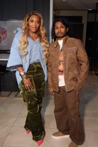 Ashwin Gane standing beside Yandy Smith both dressed in stylish outfits inside a modern venue.