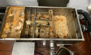 Full grease trap showing accumulated fats, oils, and grease in a commercial kitchen, emphasizing the need for professional grease trap cleaning.