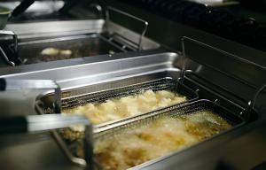 Commercial kitchen deep fryer producing used cooking oil, underscoring the need for responsible oil collection and grease management.