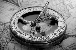 An antique hand-held sundial resting on an old map