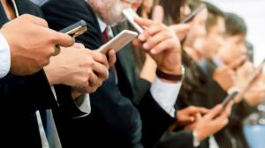 Business professionals closely reading content on their smartphones, illustrating how audiences engage with emails and AI-generated summaries on mobile devices.