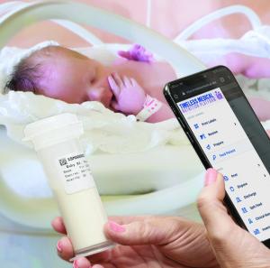 A photograph of Timeless Medical Nutrition Platform Nutrition Management Software being used to scan a baby's bottle, with a baby in an incubator in the background.