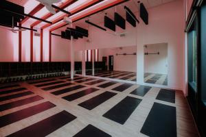 Darkened room with yoga mats and gentle hues of pink bathing walls in color.