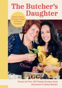 Cover image The Butcher's Daughter Cookbook, shows mother and daughter in Nonna's kitchen in front of a dish with eggplant, mozzarella, tomato and basil
