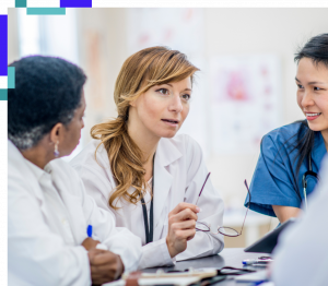 A group of podiatric medical professionals sitting together in discussion, wearing white coats and scrubs in a clinical setting.