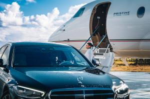 VIP passenger boarding a Pristine Jet Charter private jet with chauffeur-driven Mercedes service.