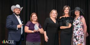 Two Arizona Economic Education Teachers of the Year stand smiling at the Champions in Education event, holding their awards in front of a black backdrop.