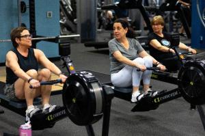 Three woman exercise on rowing machines as part of LIVESTRONG at the Y, a cancer surviorship program.