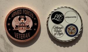 A pair of commemorative coins are displayed side-by-side to honor the Veterans Day fundraiser by Lena of Goldpawnership, Lisa of Sal Luxury, Joe Hollywood, and Mary’s House of Style, all sellers on the Whatnot live auction platform, benefiting NCHV.org.